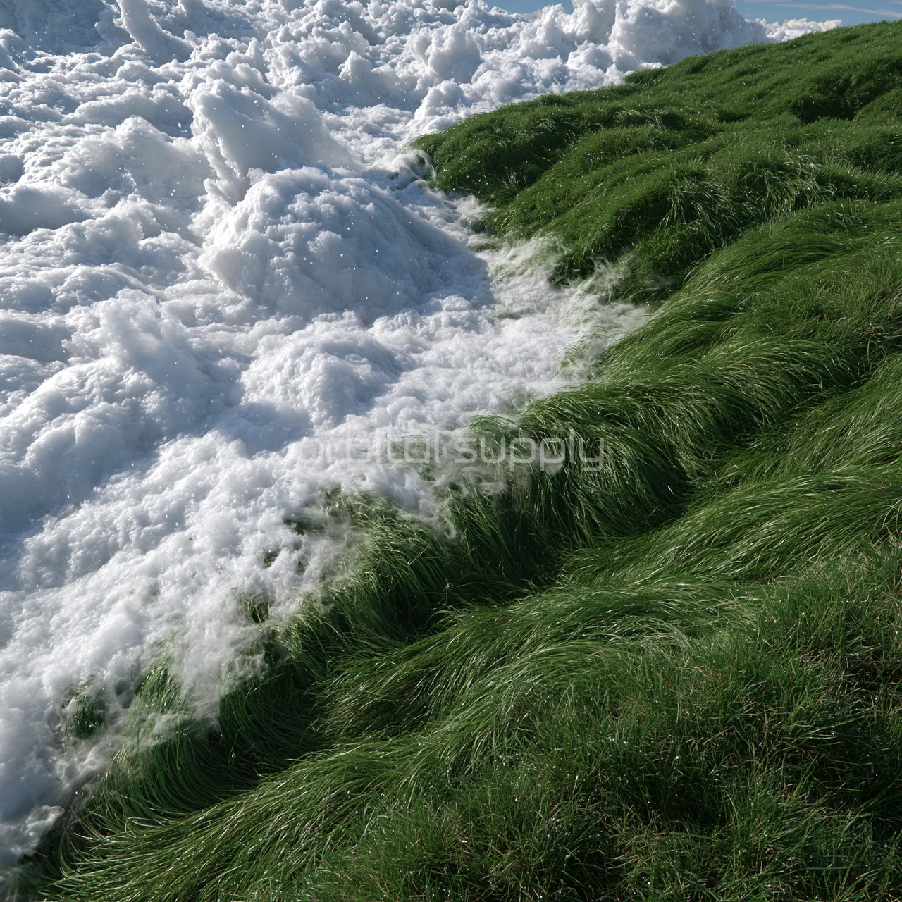 White clouds gather beside a steep lush grassy slope.