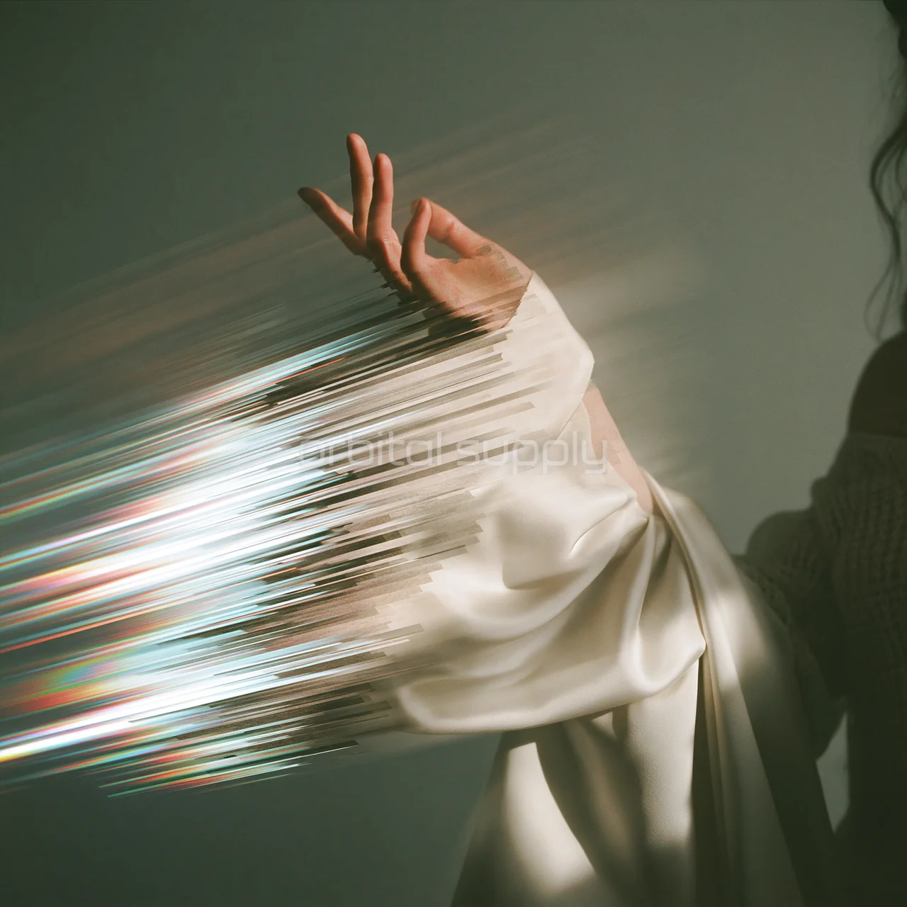A hand emerges from an ivory sleeve that breaks into luminous horizontal fragments.